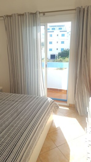 A bedroom with a bed, a sliding glass door leading to a balcony, and curtains. - Smir Parc (Allyene)