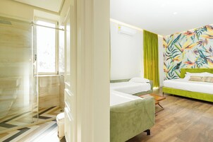 Una habitación de hotel con ducha, cama con cabecera verde y un mural de pared colorido.