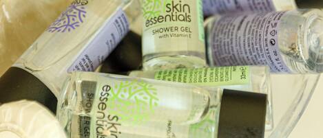 A clear glass container holding various bottles of skincare products, including a shower gel with vitamin E.