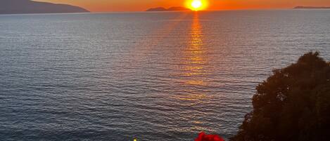 Un atardecer sobre un mar tranquilo con una masa de tierra a lo lejos.