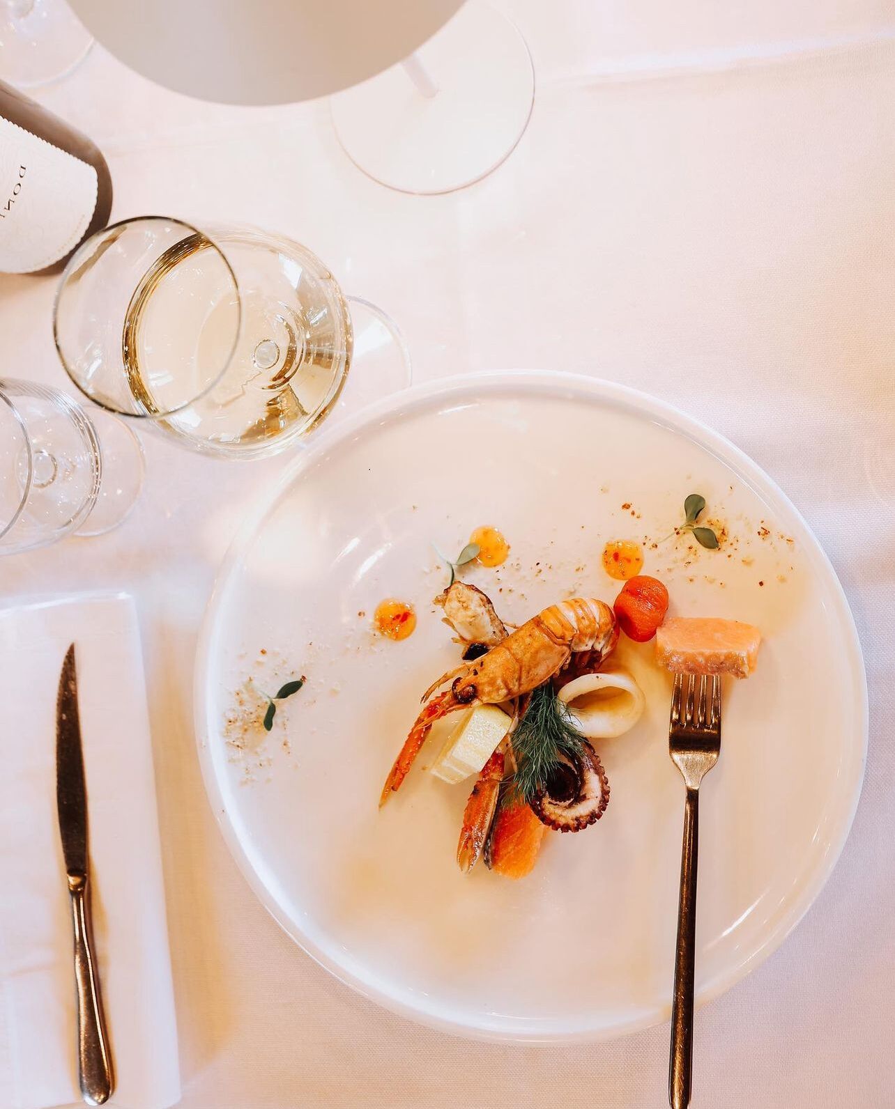 A dining table with a plate of seafood, a fork, and a knife.