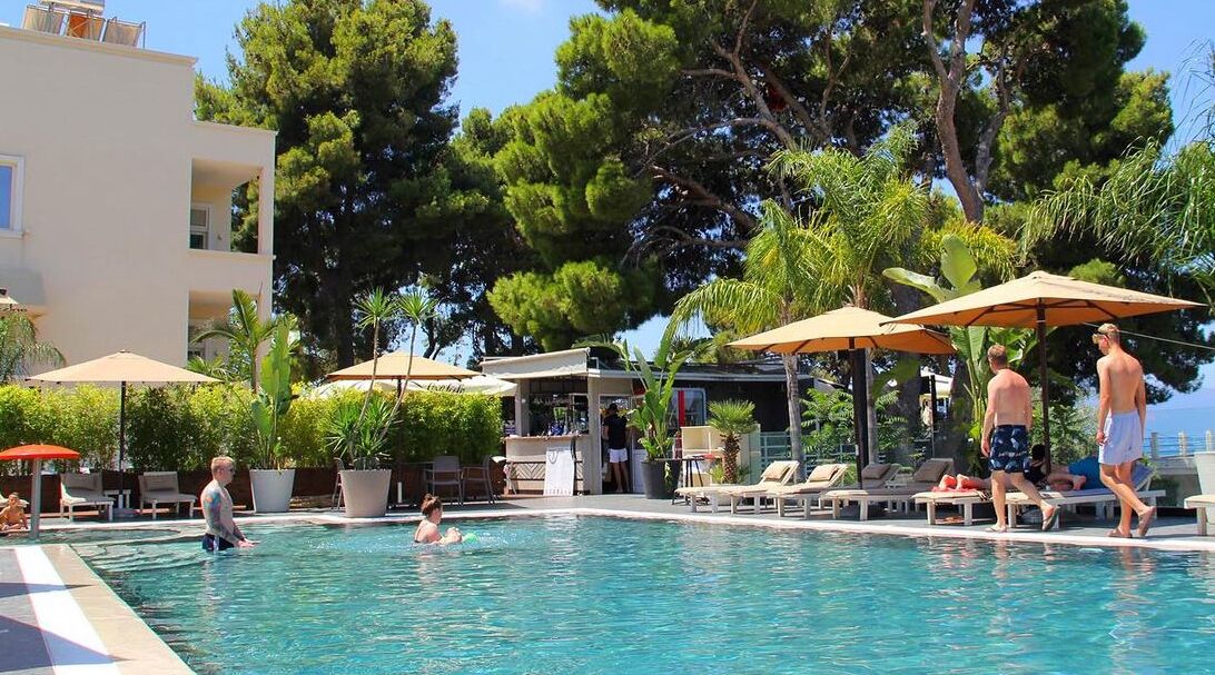 Un área de piscina con sillones de descanso, sombrillas y un bar.