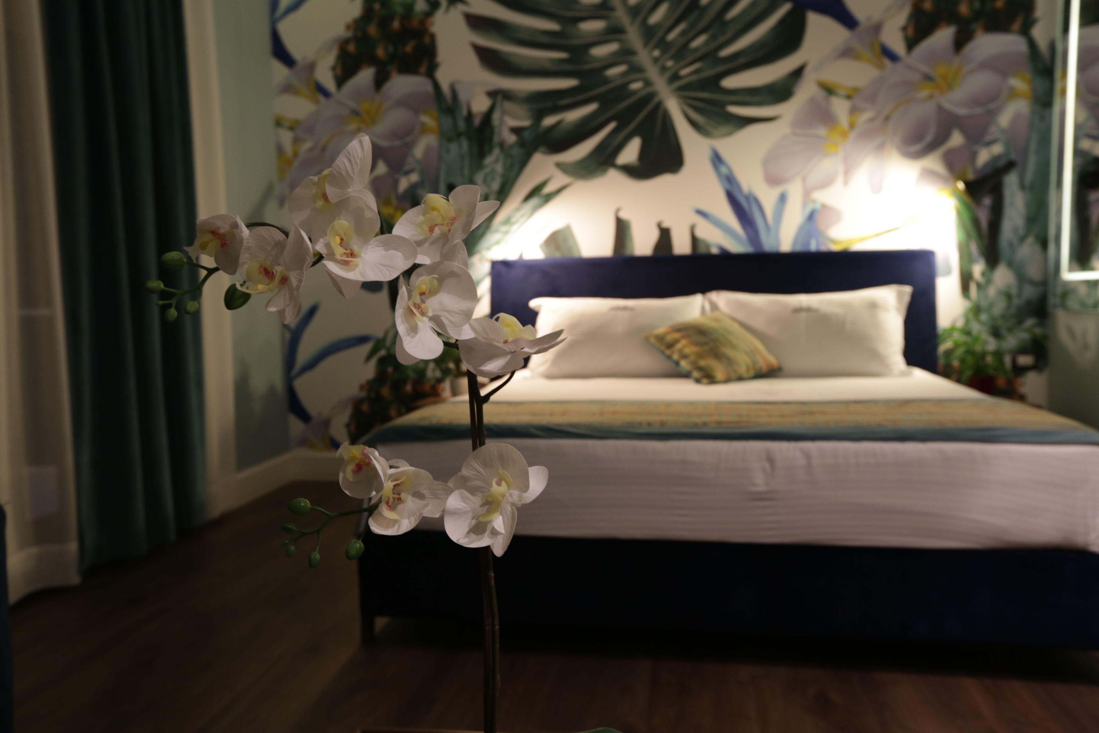 A bedroom with a bed, a nightstand, and a potted orchid.