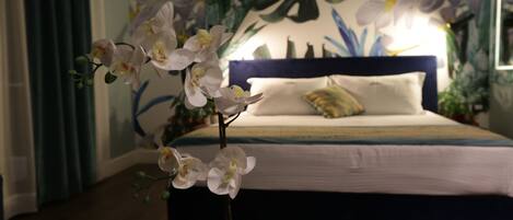 A bedroom with a bed, a nightstand, and a potted orchid.