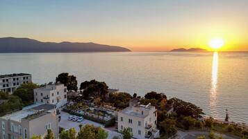 Ein Hotel an der Küste mit mehreren Gebäuden, einem Schwimmbad und Blick auf das Meer bei Sonnenuntergang.