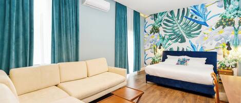 A modern bedroom with a beige sofa, a blue bed, and a wooden coffee table.