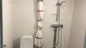 Un baño pequeño y moderno con inodoro, ducha y una toalla colgada en la pared.