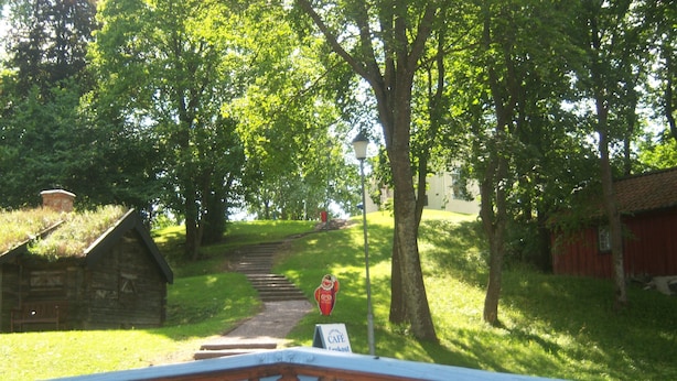 A wooden sign with the name 'Korskullen' in large letters, a stone building, a red structure, and a pathway leading uphill. - Korskullens Camping Stugor & Cafe (Soderkoping)