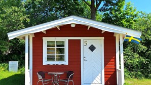 A small red building with a white door and window, a number '5' on the door, and a flag on the right. - Skeppsdockans Camping & Vandrarhem (Soderkoping)