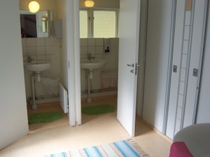 Een badkamer met twee wasbakken, een spiegel en een deur naar een andere kamer.