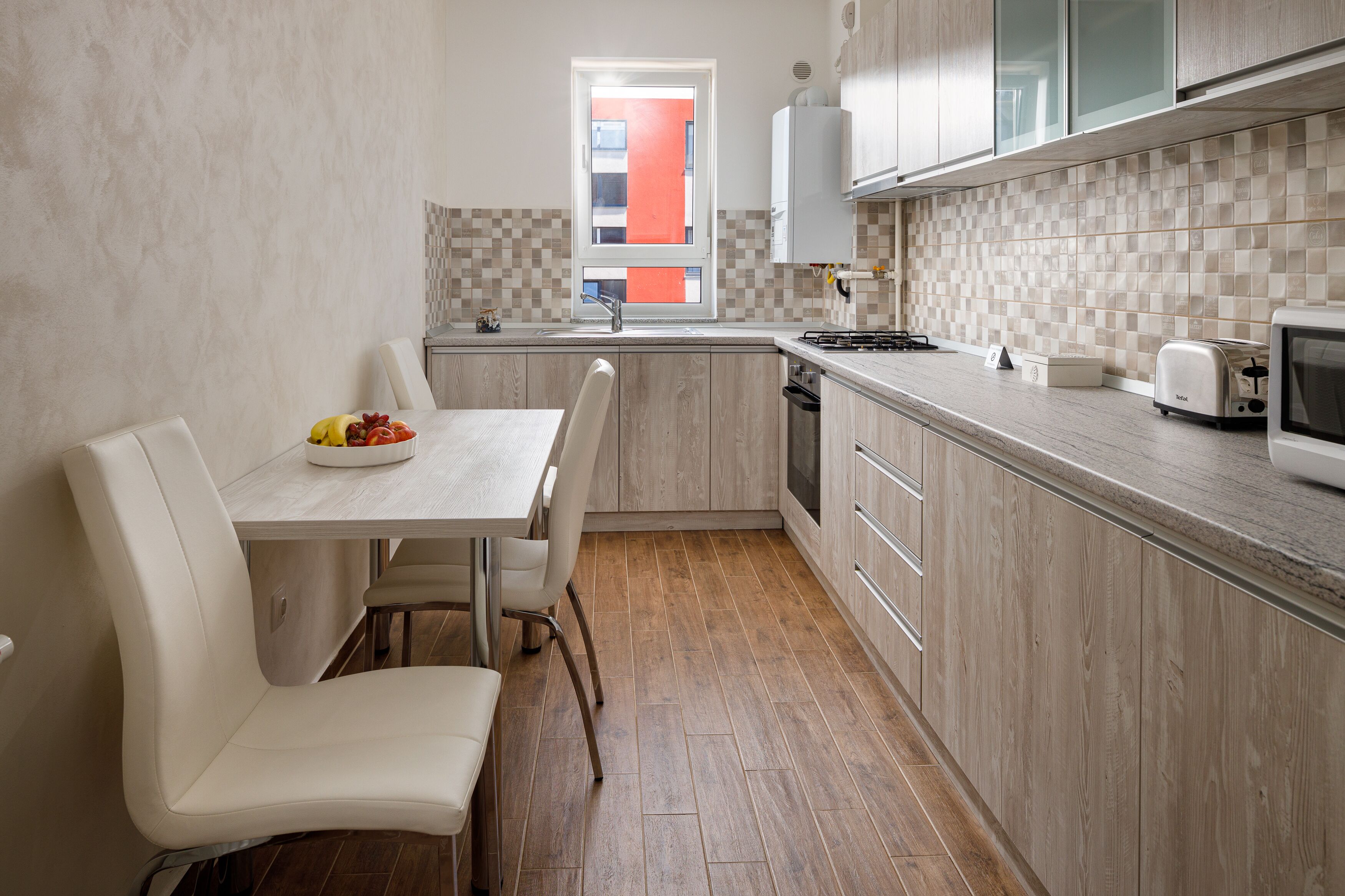 A modern kitchen with a dining table, chairs, and a microwave.