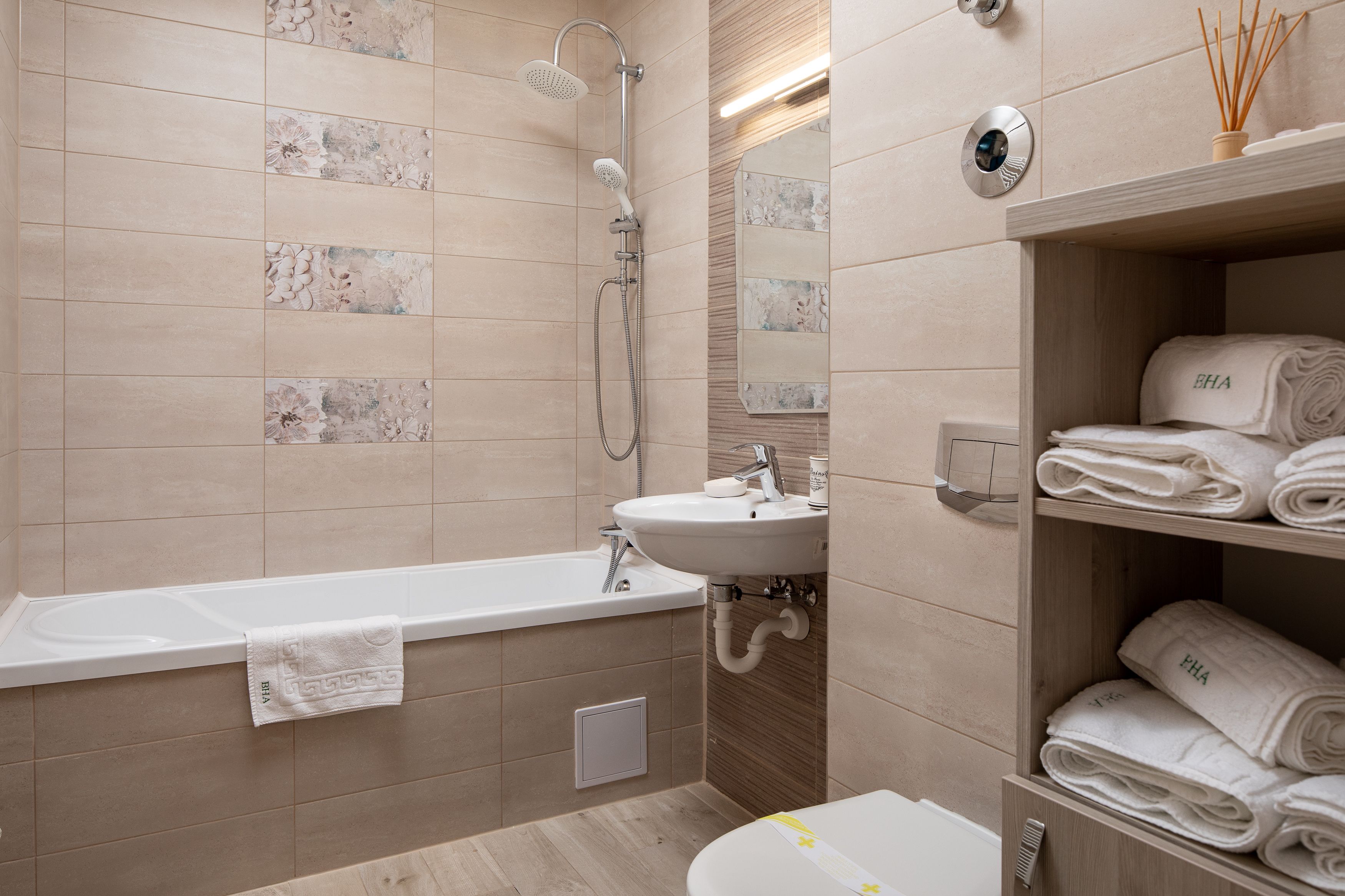 Un baño moderno con bañera, lavamanos y estante con toallas dobladas.