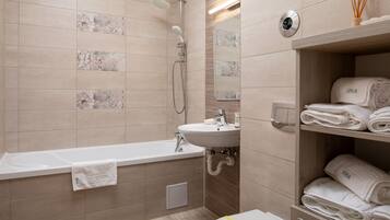 Un baño moderno con bañera, lavamanos y estante con toallas dobladas.