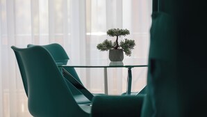A modern room with teal chairs, a glass table, and a bonsai tree on a white pot. - Brasov Holiday Apartments (Brasov)