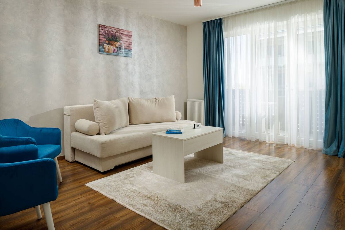 A living room with a beige sofa, a white coffee table, and a blue armchair.