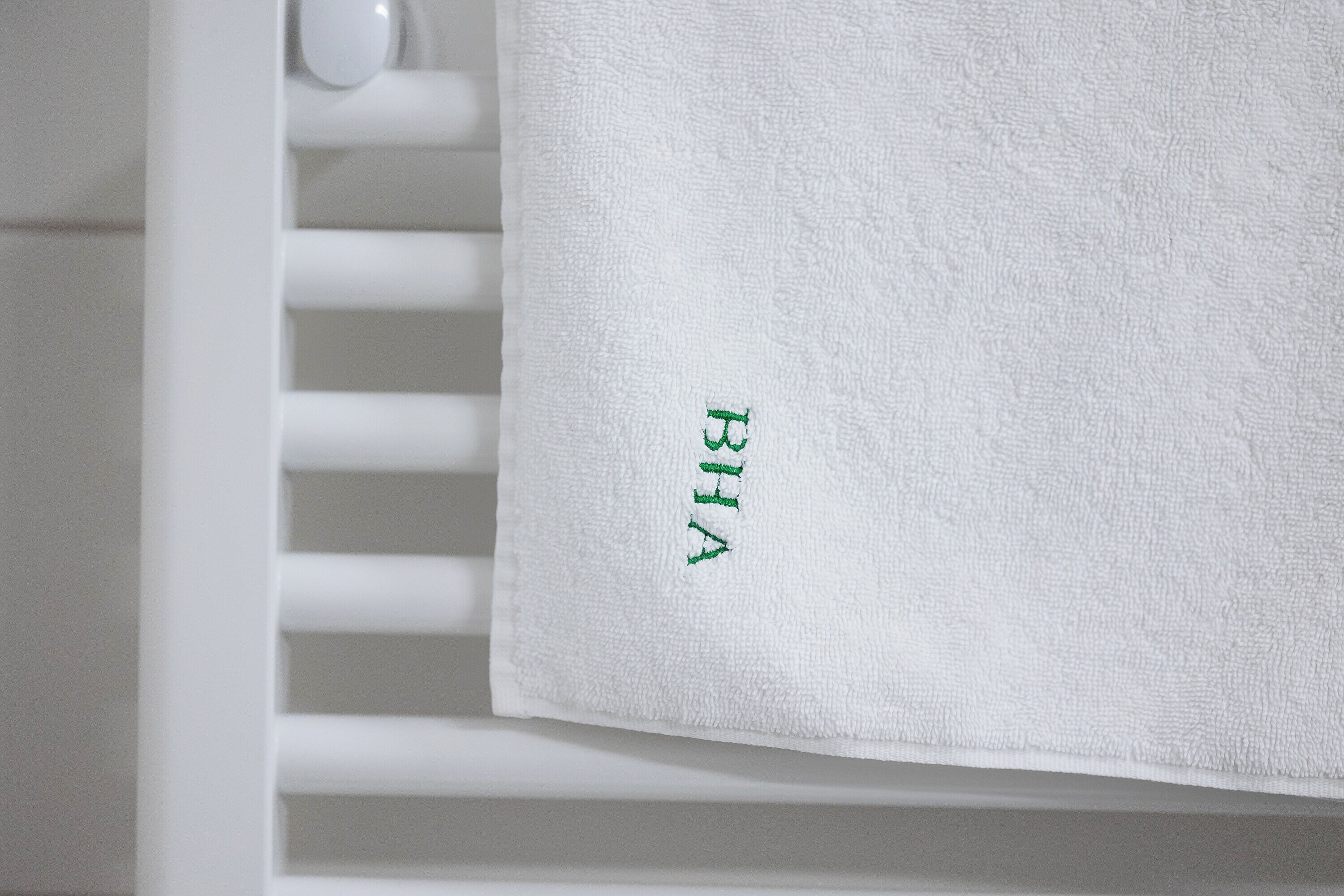 Une serviette blanche avec du texte vert brodé sur un fond blanc.