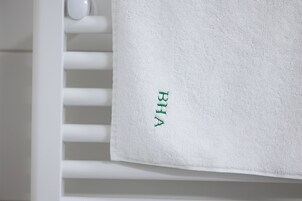 Una toalla blanca con texto bordado en verde sobre una superficie blanca.