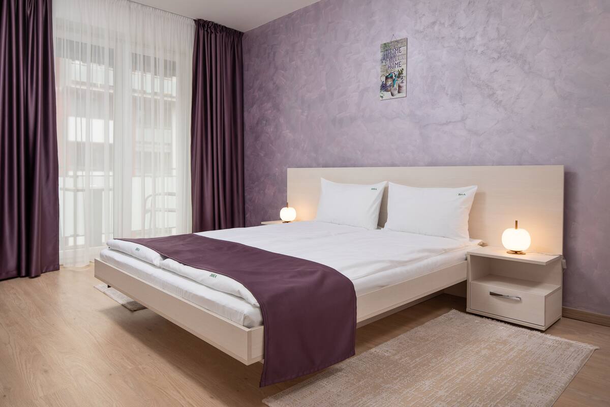 A modern bedroom with a bed, nightstands, and a wall-mounted picture.