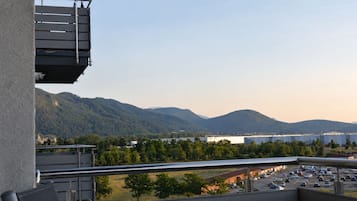 A balcony with a view of a parking lot, mountains, and a body of water.