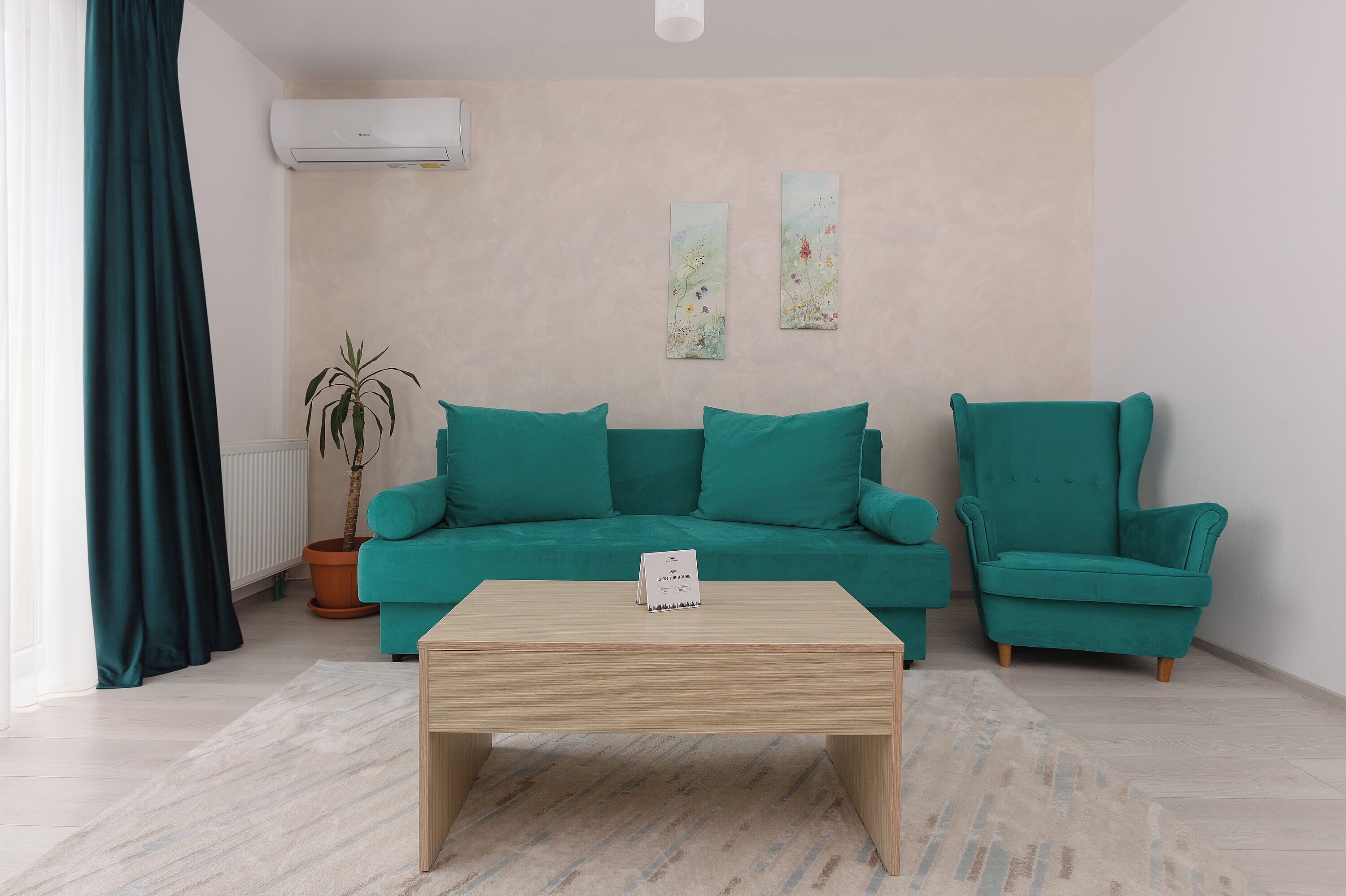 Una sala de estar moderna con un sofá azul turquesa, un sillón a juego y una mesa de centro de madera.