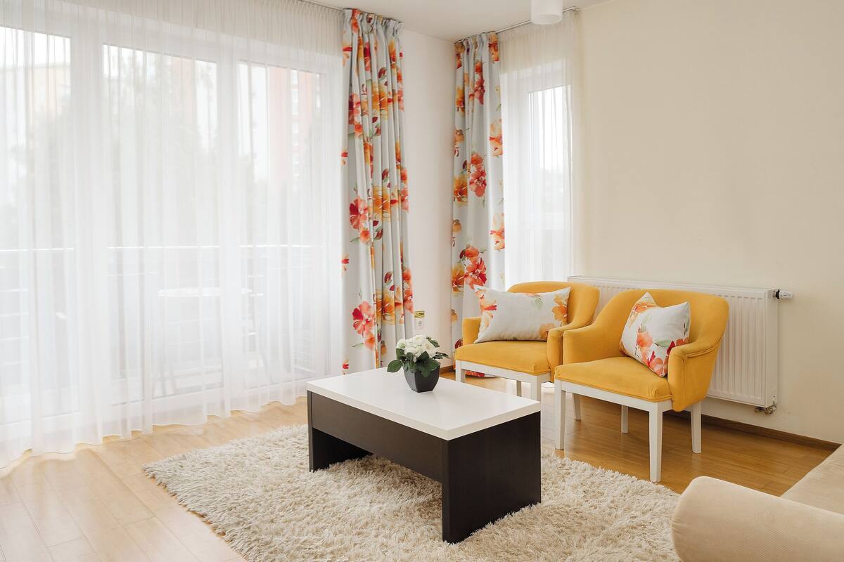 A living room with a white coffee table, a yellow sofa, and a white armchair.