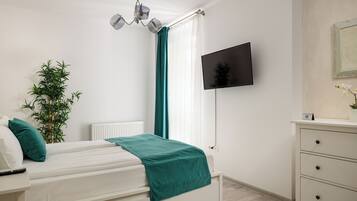 Une chambre à coucher avec un lit, une télévision, une plante et une commode.