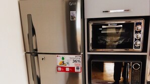 Eine kleine Küche mit einem Edelstahlkühlschrank, einem Einbauofen und einer Mikrowelle.
