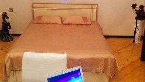 Ein Schlafzimmer mit einem Bett, einem Laptop auf einem Tisch und einem Gemälde an der Wand.