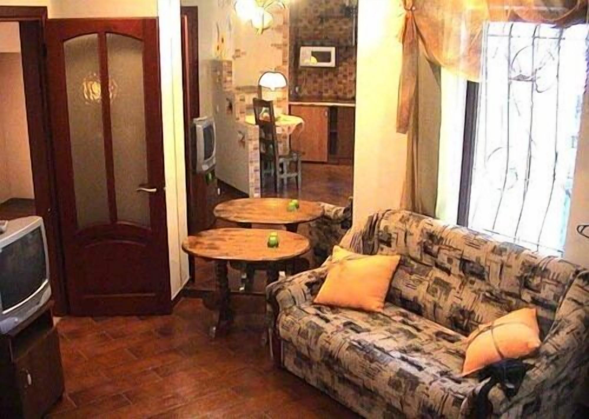 Una sala de estar con un sofá, dos mesas redondas, un televisor y una puerta.