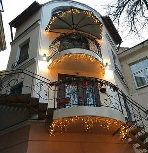 A multi-story building with balconies adorned with string lights and greenery. - Odelana Apartments (Odesa)