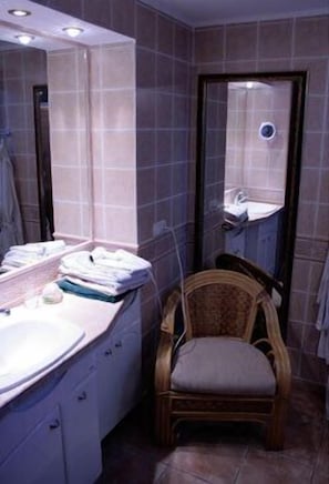 A bathroom with a sink, mirror, and chair.