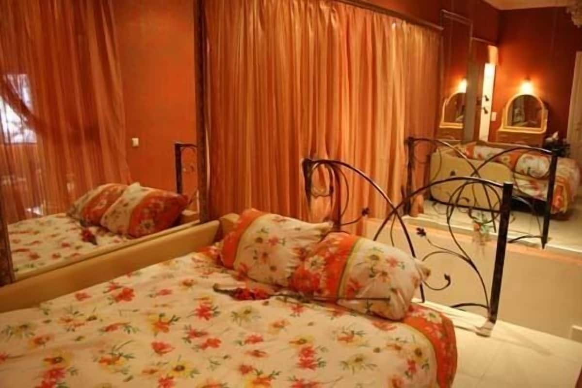 A bedroom with two beds, floral bedding, and a mirror reflecting the room.