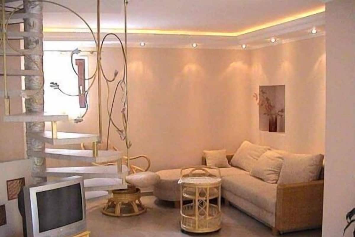 A modern living room with a sectional sofa, a television, and a decorative hanging structure.