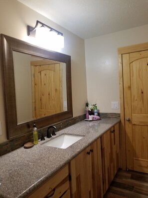 A bathroom with a wooden vanity, a sink, and a large mirror.
