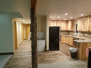 Eine moderne Küche mit Holzschränken, einem schwarzen Kühlschrank und einer gefliesten Spritzschutzwand.