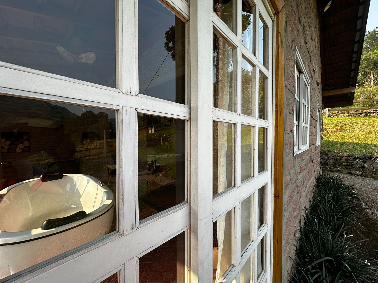 Een gebouw met veel ramen, waarvan er een paar open zijn, en een zichtbaar buitengebied met gras en een stenen muur.