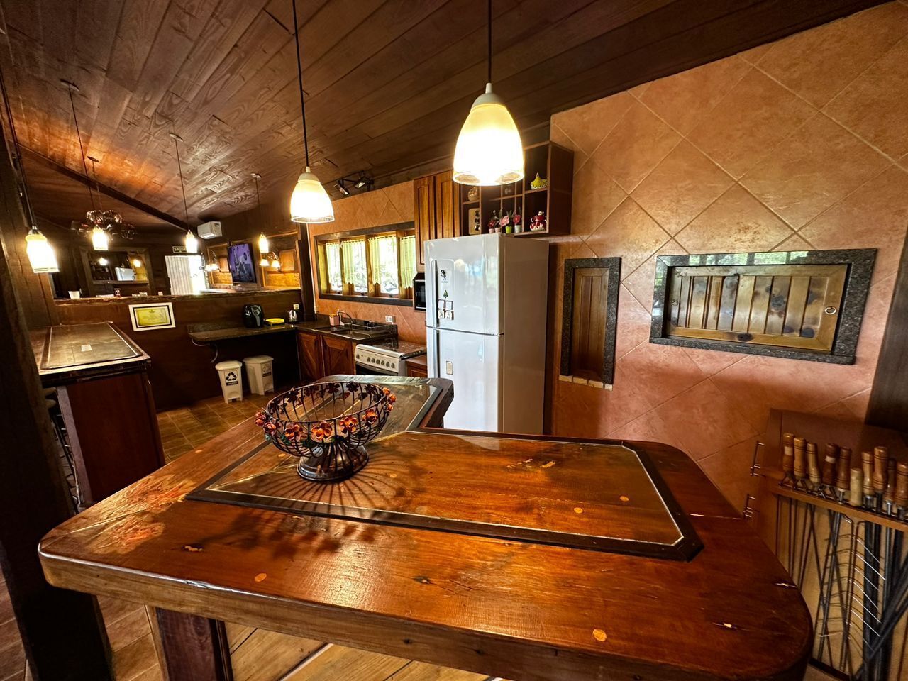 Une cuisine rustique avec des plans de travail en bois, un îlot central, des luminaires suspendus et un réfrigérateur.