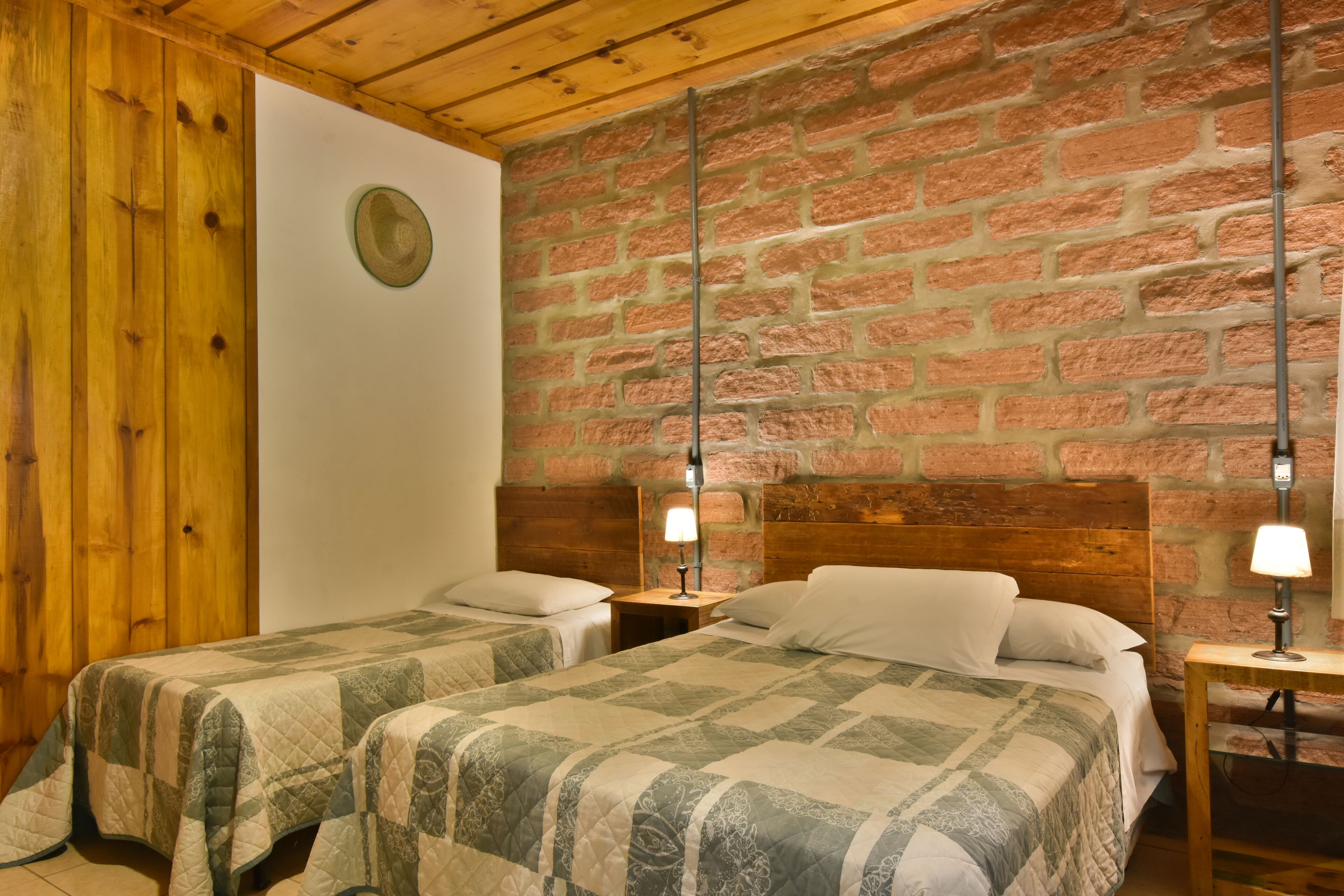 Una habitación con dos camas, paredes de madera y un muro de ladrillo.