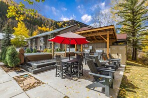 Un espace extérieur aménagé avec des tables et des chaises, un jacuzzi et un barbecue.