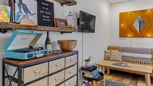 Ein gemütliches Wohnzimmer mit einem Vintage-Jukebox, einem Flachbildfernseher, einer Holz-Wanddekoration und einem bequemen Sofa.