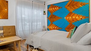 Ein Schlafzimmer mit einem Bett, einem Nachttisch, einem Sessel und einer großen Wanddekoration.