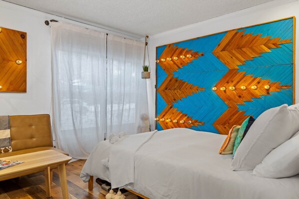 Une chambre à coucher comprenant un lit, une table de chevet, une chaise et un grand élément décoratif mural.