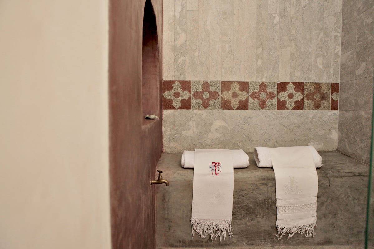 Une salle de bain avec un sol en pierre, une porte en bois et un porte-serviettes avec deux serviettes.