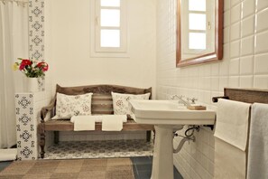 A bathroom with a wooden bench, a sink, and a mirror. - Antica Dimora la Porta del Sale (Marsala)