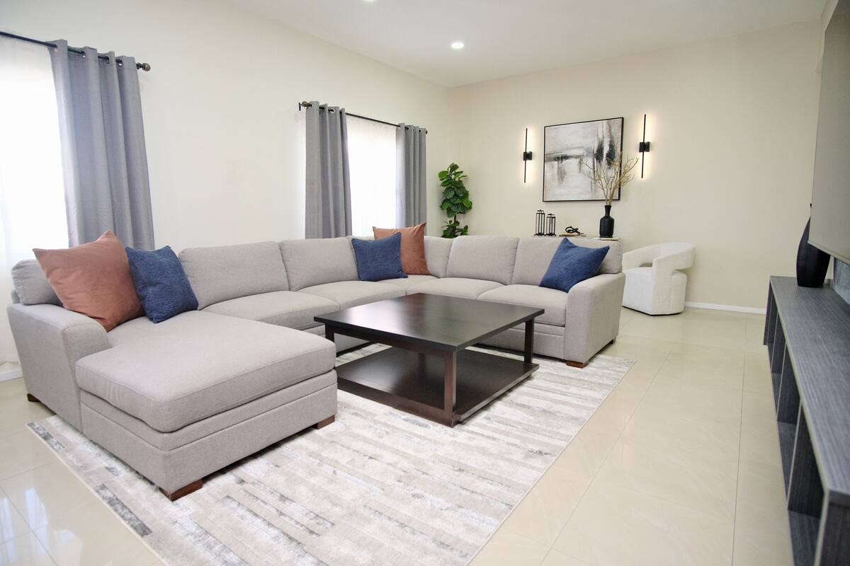 A modern living room with a sectional sofa, a coffee table, and a TV stand.