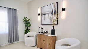 A modern living room with a white sofa, a wooden cabinet, and a large abstract painting. - Rio Suites (Tijuana)
