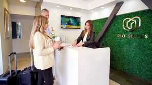 A reception desk with a green wall and a logo for Rio Suites. - Rio Suites (Tijuana)