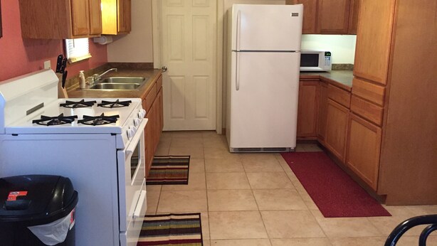 A compact kitchen with wooden cabinets, a white refrigerator, a stove, and a microwave. - Cozy Corner Mascoutah  (Mascoutah)