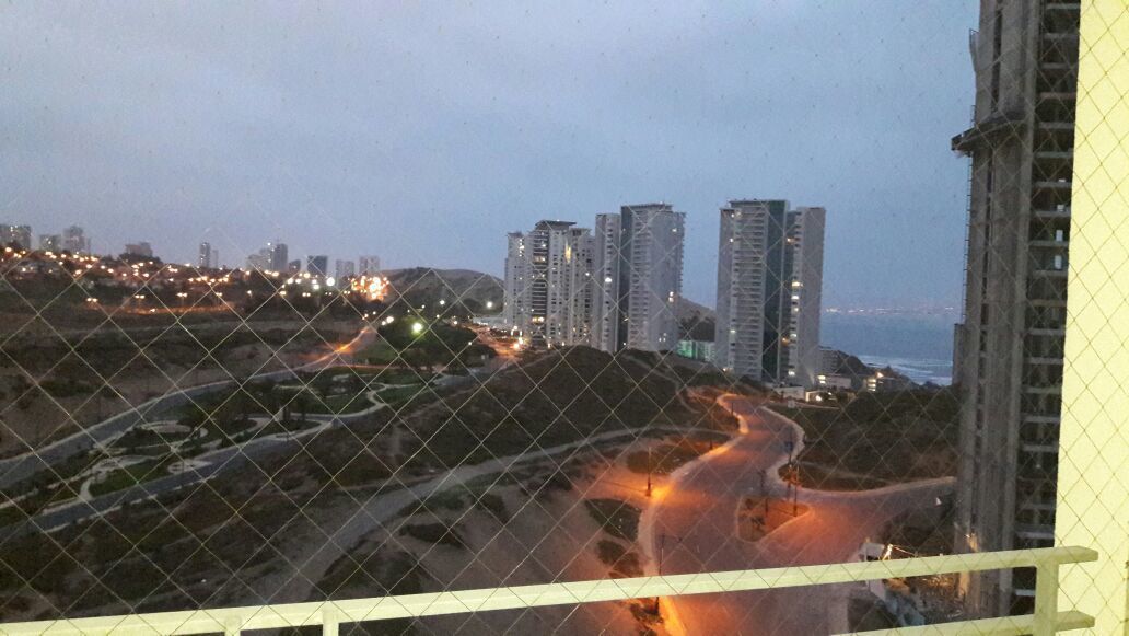 Paesaggio urbano con grattacieli, una strada tortuosa e uno specchio d'acqua sullo sfondo.