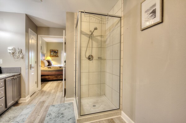 A modern bathroom with a glass-enclosed shower, a visible toilet, and a sink.